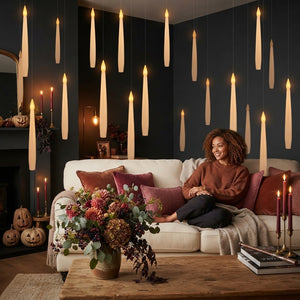 A woman relaxing in a cozy, dark-themed living room decorated with floating LED candles that create a magical atmosphere.